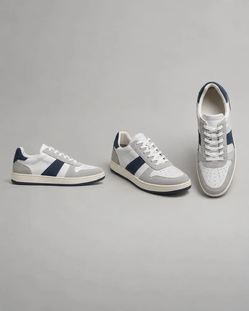 White and navy low-top sneaker photographed from the side, front angle, and above on gray.